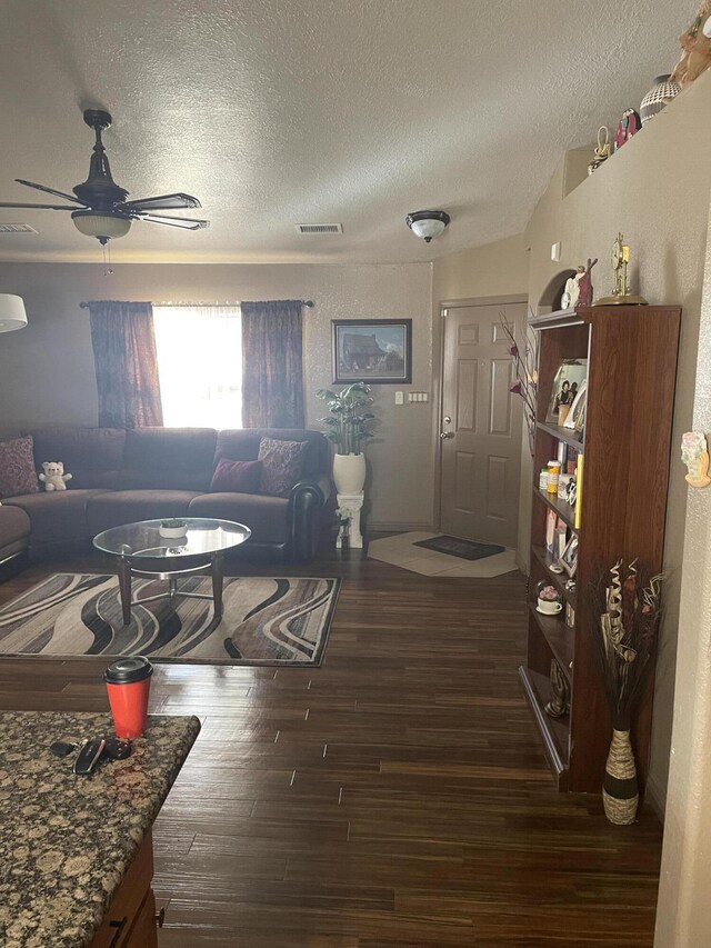 living room featuring a textured ceiling, dark hardwood / wood-style floors, and ceiling fan