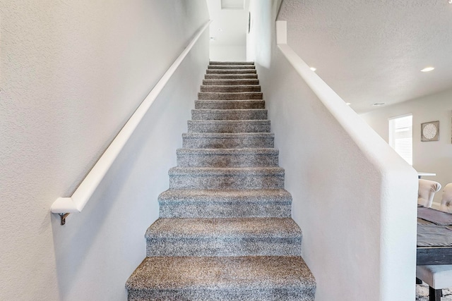 stairway featuring a textured ceiling