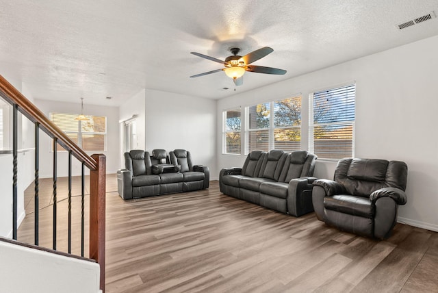 living room with hardwood / wood-style floors, ceiling fan, and a textured ceiling