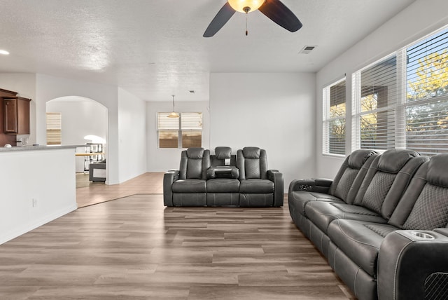 living room with a textured ceiling, light hardwood / wood-style flooring, and ceiling fan