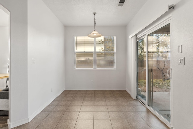 unfurnished dining area with light tile patterned floors and a textured ceiling