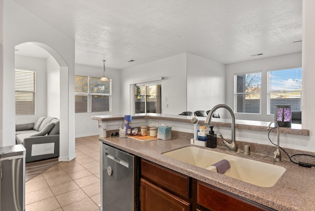 kitchen with a textured ceiling, dishwasher, pendant lighting, and sink