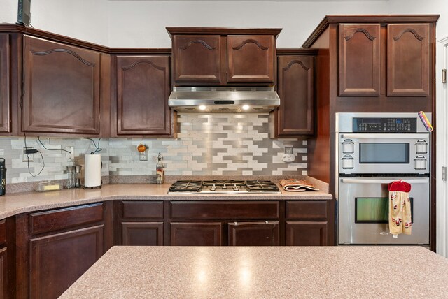 6923 Wrangell Loop NE, Rio Rancho, NM 87144 - kitchen with extractor fan, appliances with stainless steel finishes, dark brown cabinets, and decorative backsplash