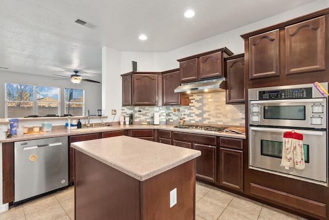 kitchen featuring kitchen peninsula, appliances with stainless steel finishes, a textured ceiling, ceiling fan, and sink