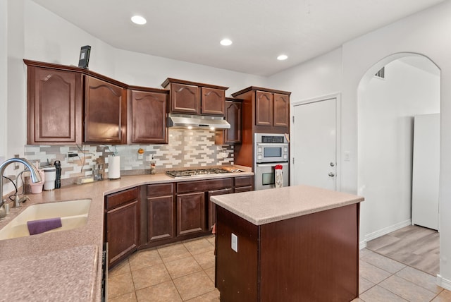 kitchen with sink, light tile patterned floors, stainless steel gas cooktop, backsplash, and a kitchen island