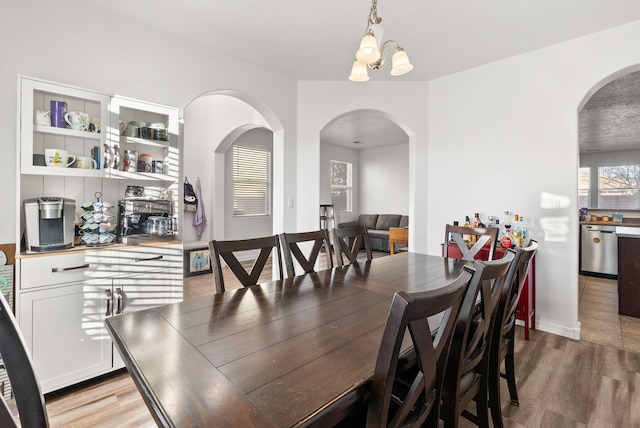 dining room with a textured ceiling, a notable chandelier, and light wood-type flooring