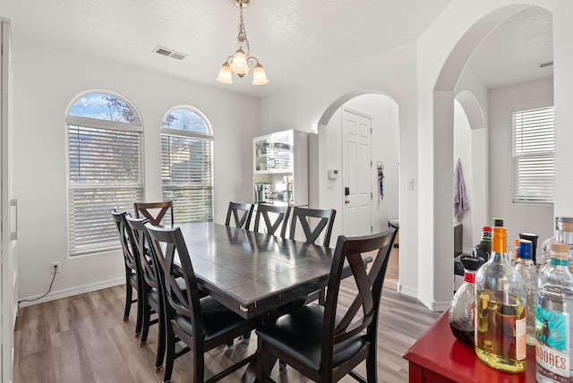 dining area featuring wood-type flooring, a textured ceiling, and a notable chandelier