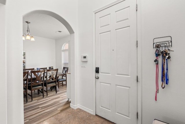 foyer featuring light hardwood / wood-style flooring, a textured ceiling, and an inviting chandelier