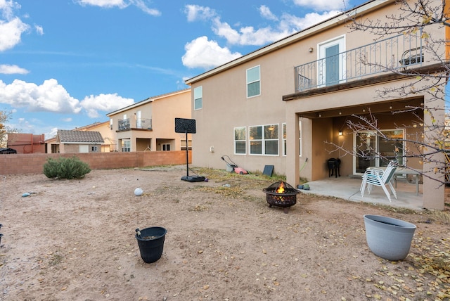 rear view of house with a patio area, a balcony, and an outdoor fire pit