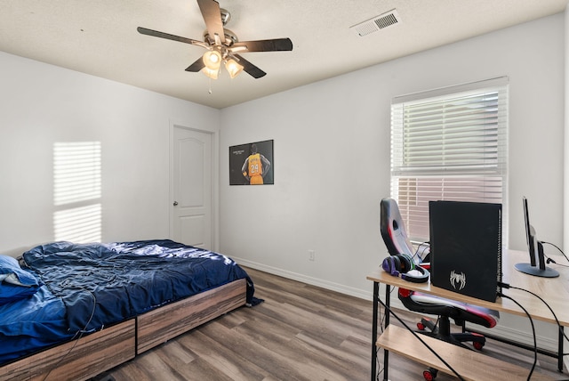 bedroom with a textured ceiling, hardwood / wood-style flooring, and ceiling fan