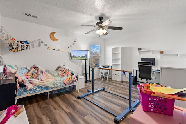 bedroom with ceiling fan, wood-type flooring, and a textured ceiling