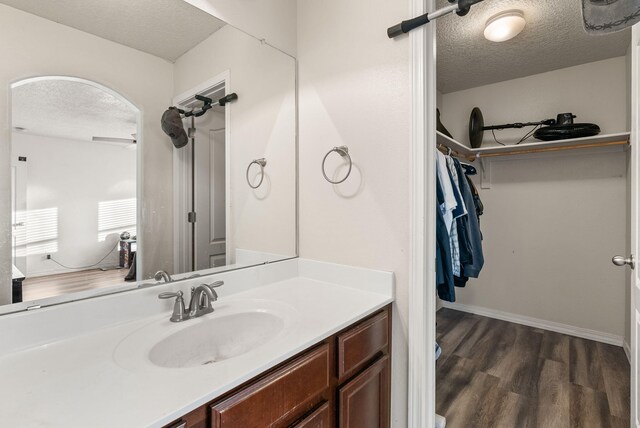 6923 Wrangell Loop NE, Rio Rancho, NM 87144 - bathroom with a textured ceiling, vanity, wood finished floors, and a walk in closet