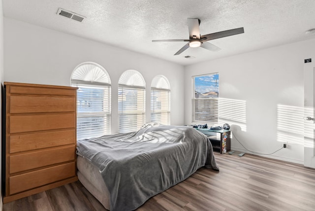 bedroom with wood-type flooring, a textured ceiling, and ceiling fan