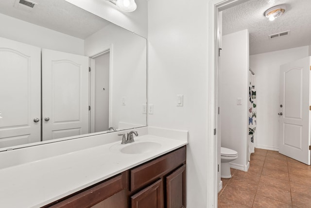 bathroom with tile patterned flooring, vanity, toilet, and a textured ceiling