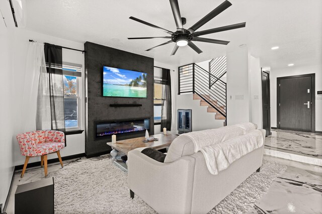 living room featuring ceiling fan, a fireplace, and a wall unit AC