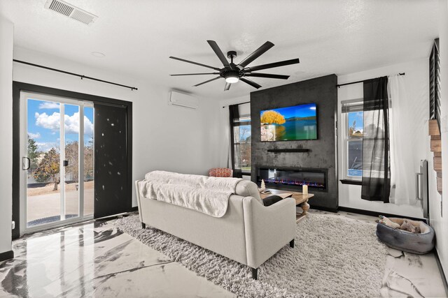 living room with ceiling fan, a large fireplace, a textured ceiling, and a wall unit AC