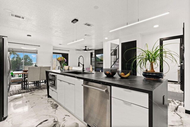 kitchen featuring a textured ceiling, decorative light fixtures, white cabinetry, and sink