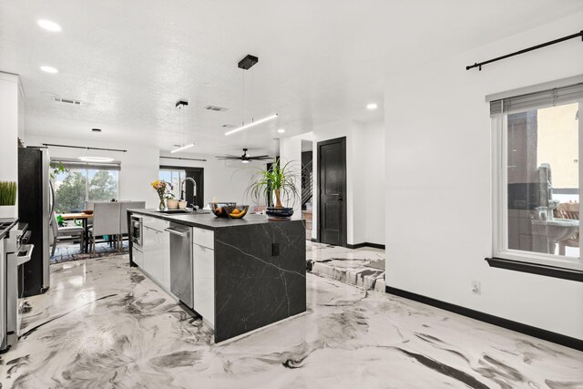 kitchen featuring ceiling fan, sink, stainless steel appliances, a textured ceiling, and decorative light fixtures