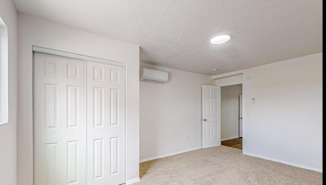 unfurnished bedroom with a wall mounted AC, a textured ceiling, carpet floors, and a closet