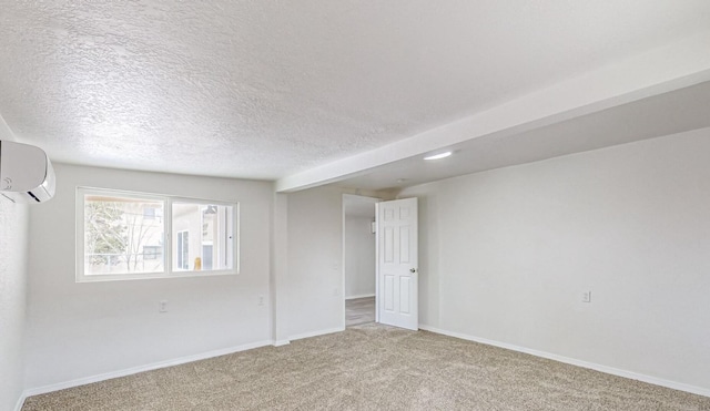 spare room featuring an AC wall unit, light carpet, and a textured ceiling