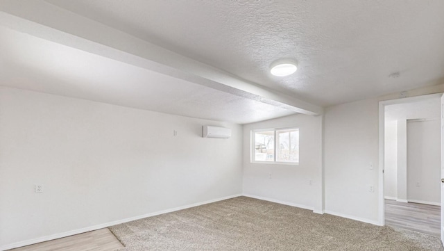 basement with carpet flooring, a textured ceiling, and a wall unit AC