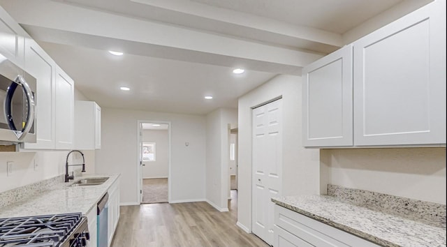 kitchen featuring white cabinetry, light stone counters, and sink