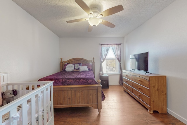 bedroom with ceiling fan, hardwood / wood-style floors, and a textured ceiling