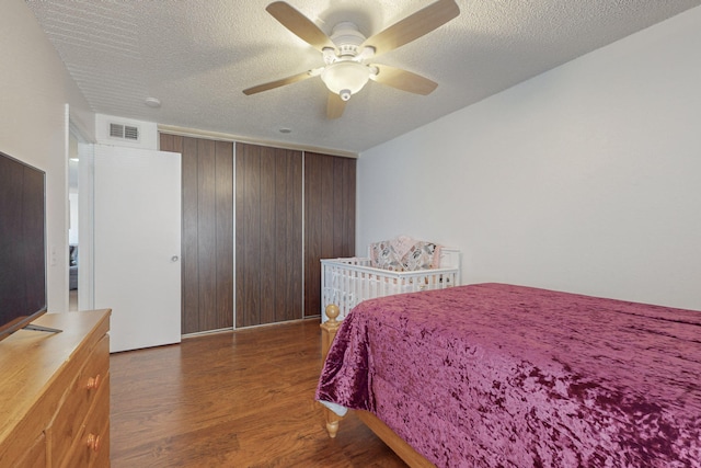 bedroom featuring a textured ceiling, dark hardwood / wood-style flooring, a closet, and ceiling fan