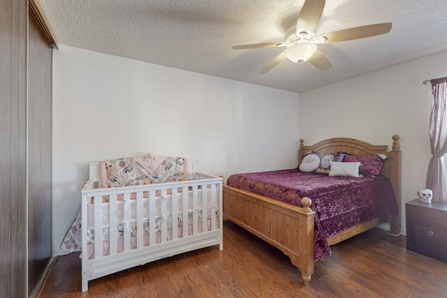 bedroom with ceiling fan, dark hardwood / wood-style flooring, and a textured ceiling