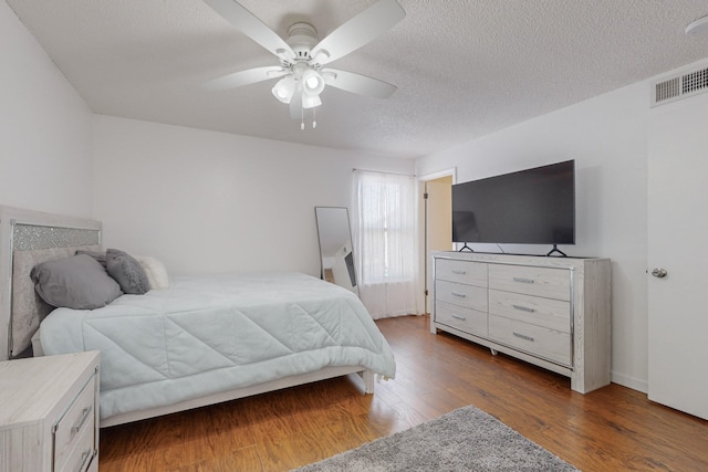 bedroom with a textured ceiling, ceiling fan, and dark wood-type flooring