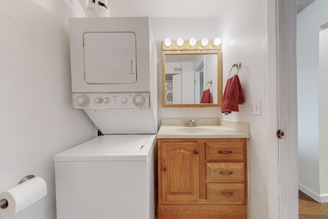 laundry area with hardwood / wood-style flooring, stacked washer / drying machine, and sink