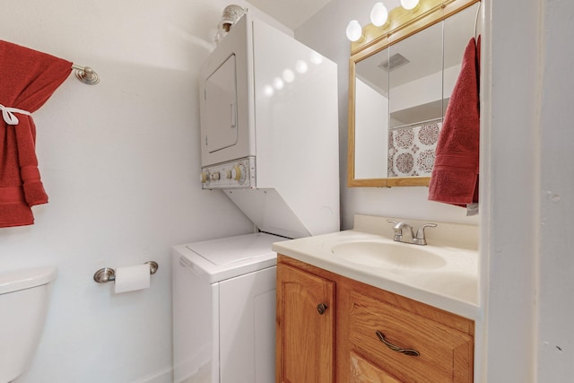 bathroom with vanity, stacked washer and clothes dryer, and toilet