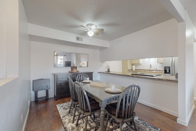 dining area with a textured ceiling, ceiling fan, dark wood-type flooring, and sink