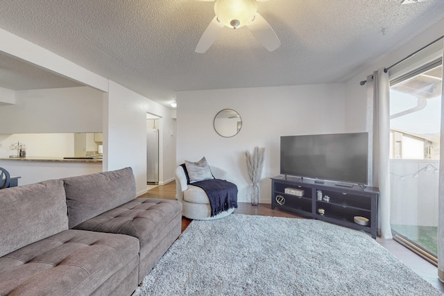 living room featuring ceiling fan, wood-type flooring, and a textured ceiling