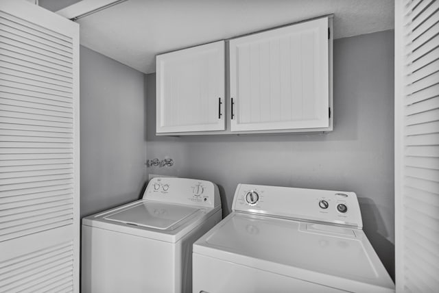 laundry area featuring washer and dryer, cabinets, and a textured ceiling