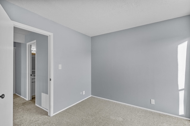 spare room featuring light colored carpet and a textured ceiling