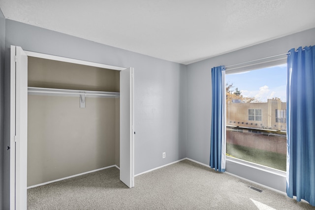 unfurnished bedroom with a closet, carpet flooring, and multiple windows