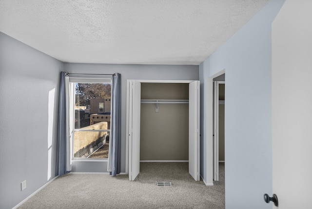 unfurnished bedroom with light colored carpet and a textured ceiling