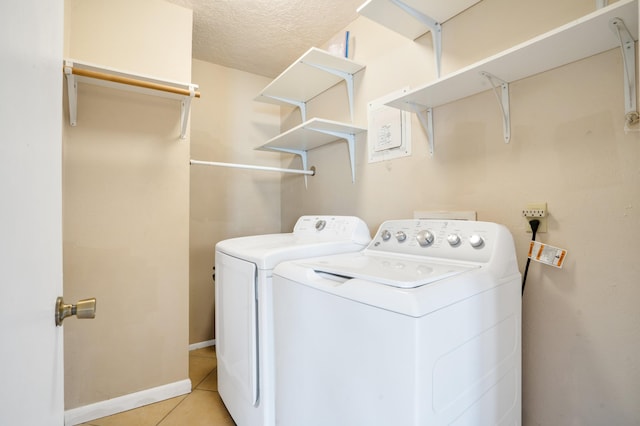 laundry area with washer and dryer, a textured ceiling, and light tile patterned flooring