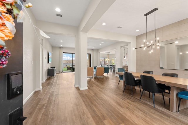 dining area featuring light wood-type flooring and an inviting chandelier