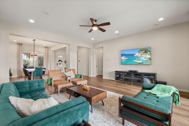 living room with light hardwood / wood-style flooring and ceiling fan with notable chandelier