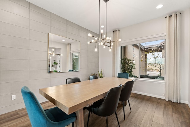 dining space with dark hardwood / wood-style floors, tile walls, and an inviting chandelier