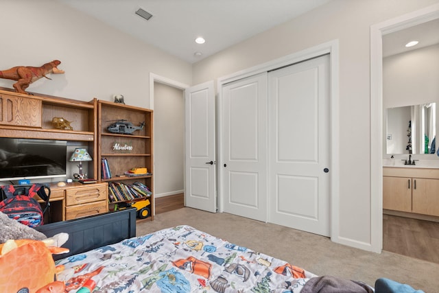 carpeted bedroom with connected bathroom, a closet, and sink