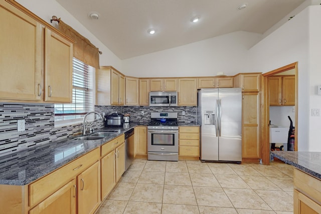 kitchen featuring stainless steel appliances, vaulted ceiling, dark stone counters, and sink