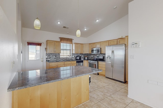 kitchen featuring backsplash, sink, hanging light fixtures, dark stone countertops, and stainless steel appliances