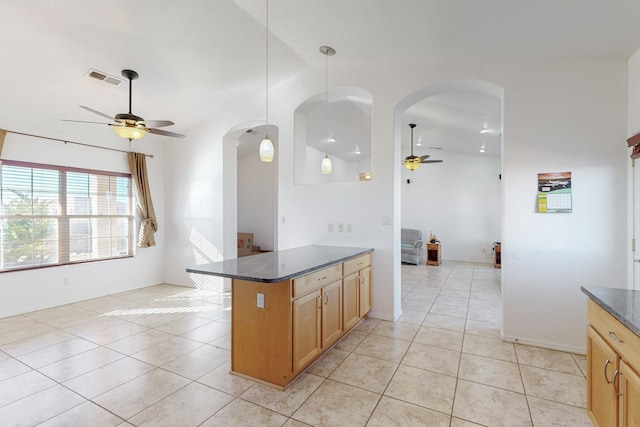 kitchen with dark stone counters, vaulted ceiling, ceiling fan, light tile patterned floors, and decorative light fixtures