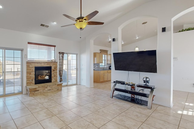 living room featuring ceiling fan, light tile patterned floors, a fireplace, and vaulted ceiling