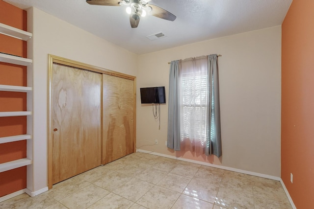 unfurnished bedroom with ceiling fan, light tile patterned floors, a textured ceiling, and a closet