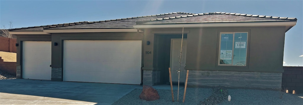 view of front of home with a tile roof, a garage, driveway, and stucco siding