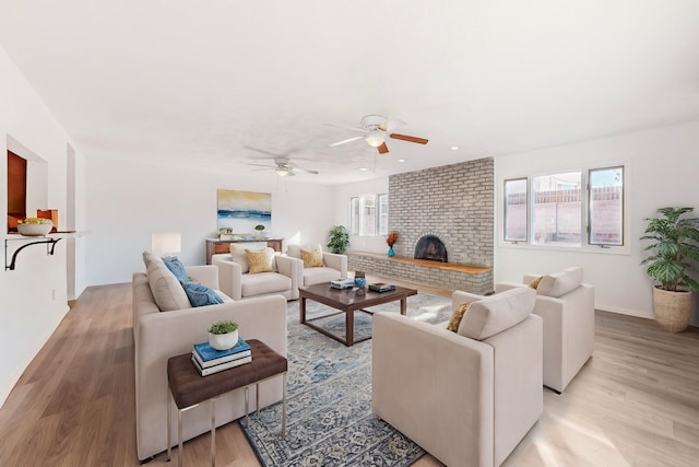 living room with a fireplace, ceiling fan, and light hardwood / wood-style flooring